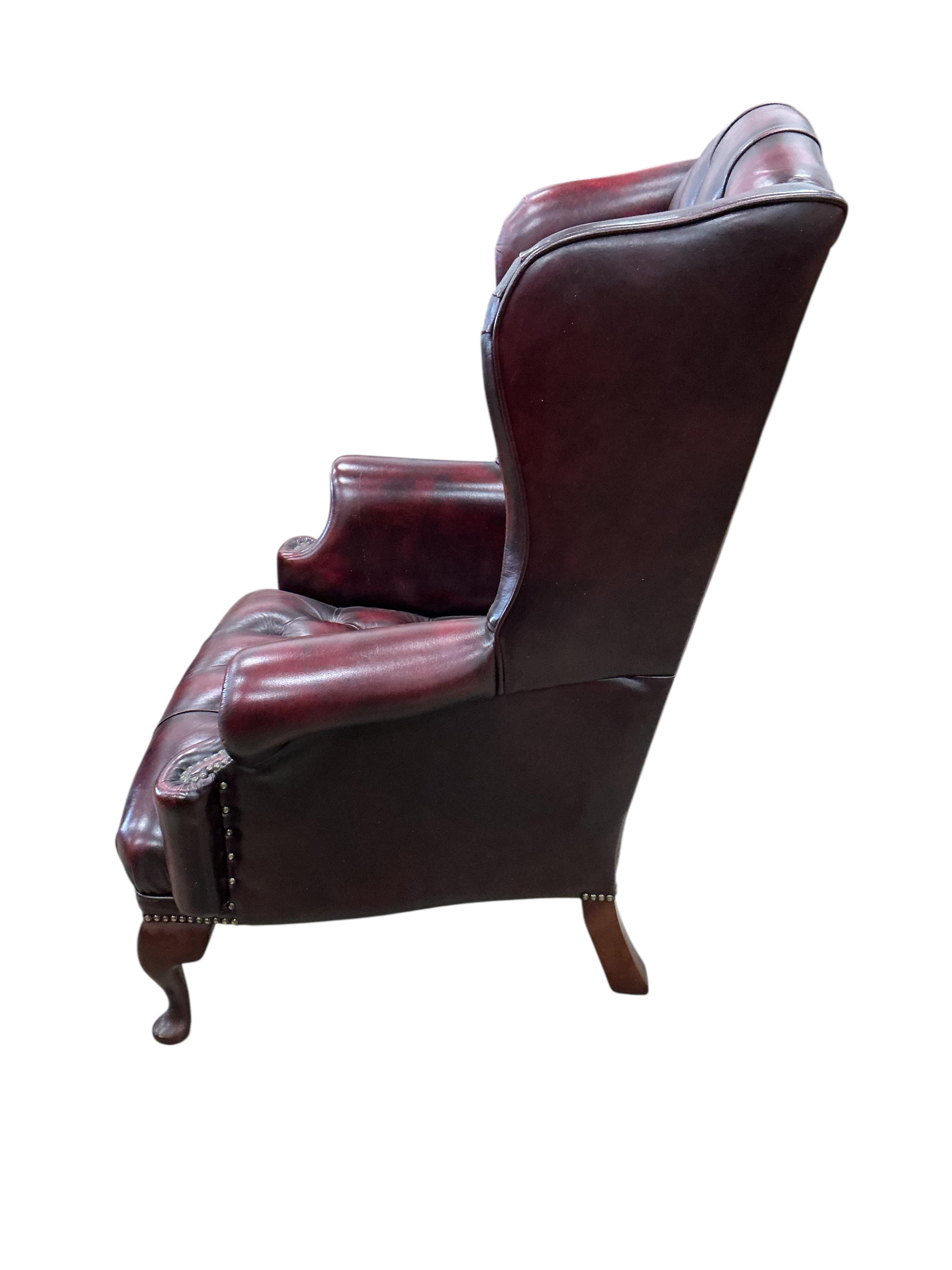 A pair of reproduction buttoned burgundy leather wing armchairs, width 82cm, depth 70cm, height 104cm